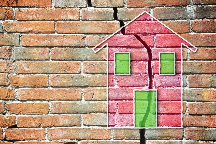 Cracked brick wall with a colored house drawn on it